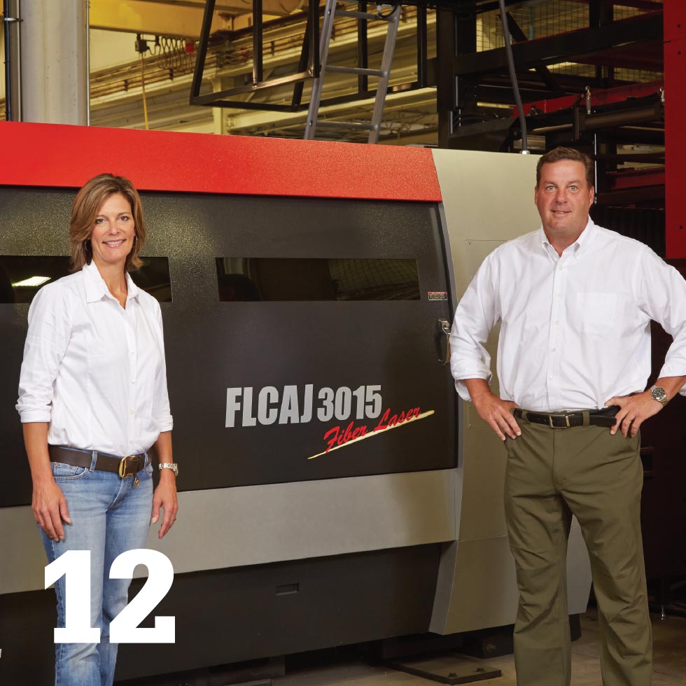 Woman and man standing by fabrication machine