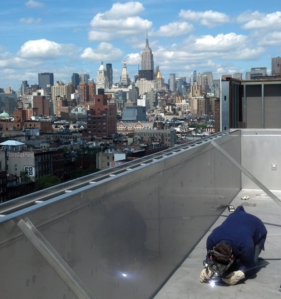 man welding with New York City skyline in the background