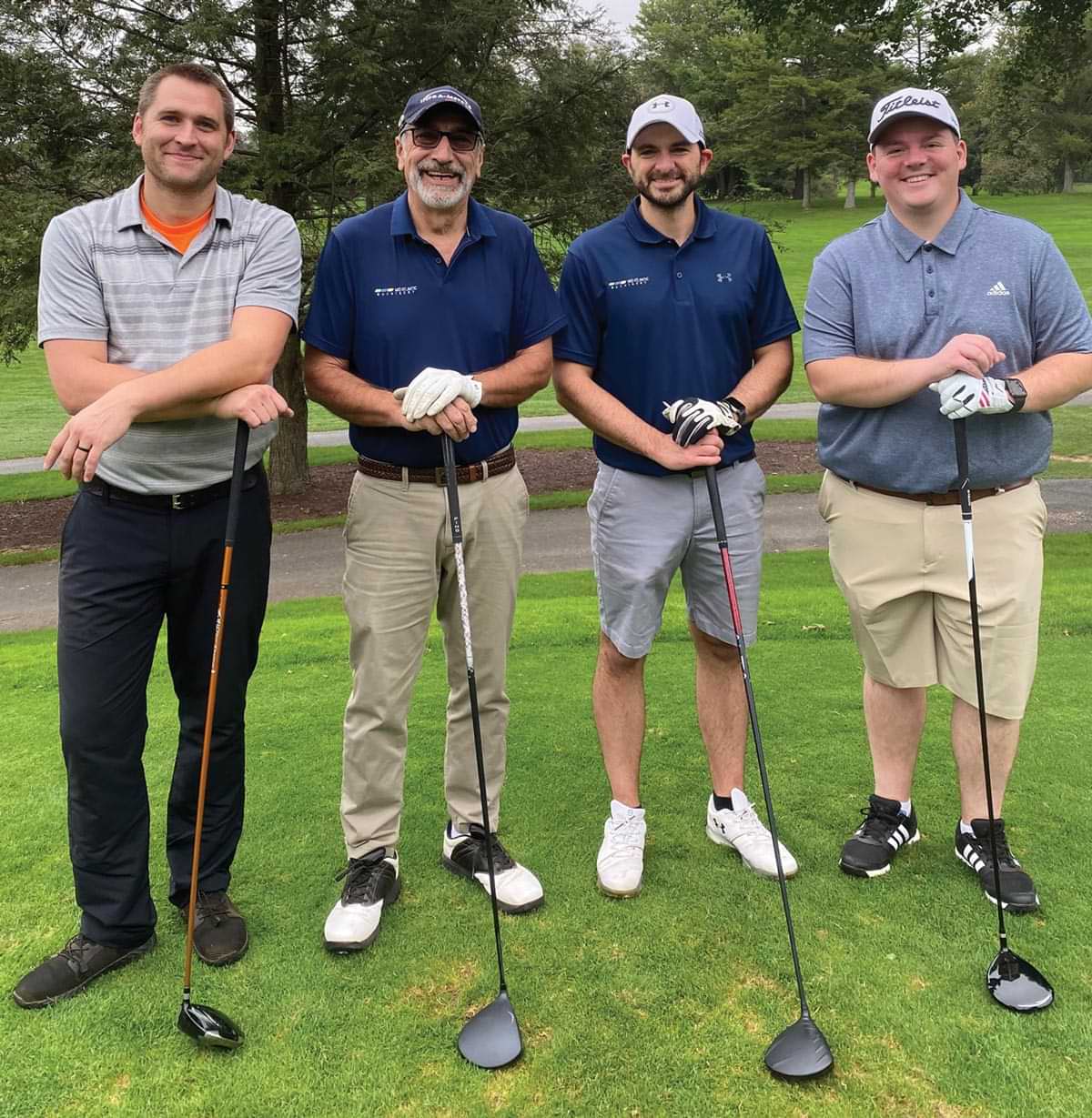 four attendees of Mid Atlantic Machinery's golf outing smiling, standing shoulder to shoulder