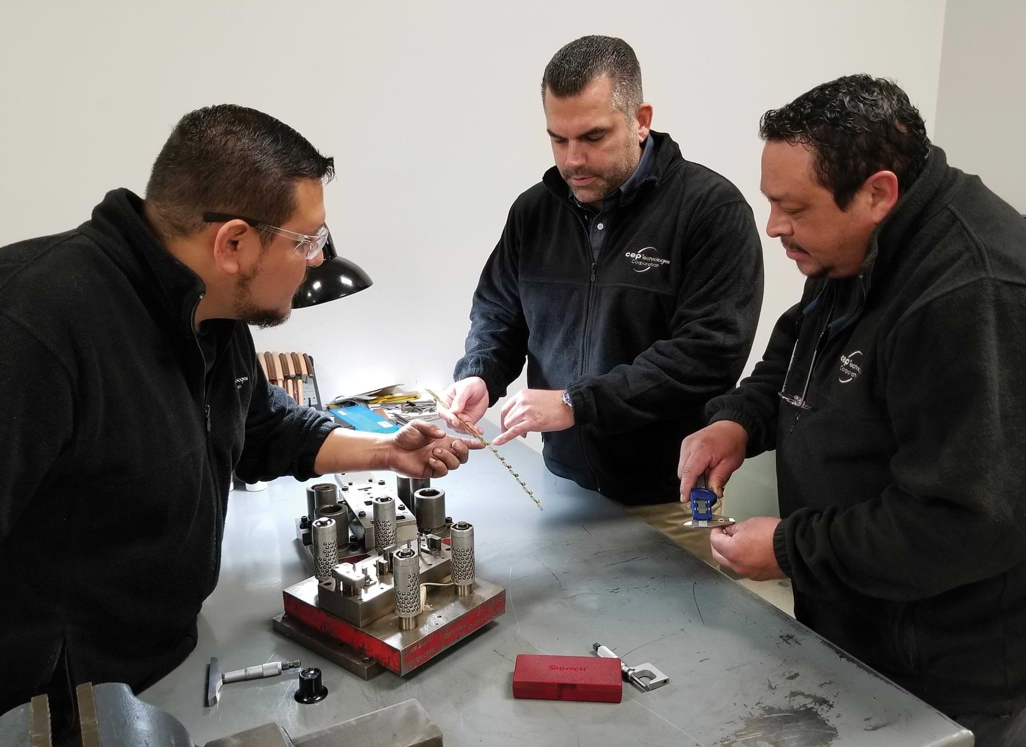 a company president and two technicians examine a customer's part